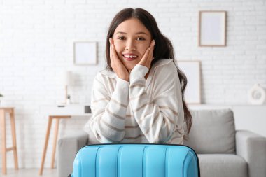 Evinde bavuluyla mutlu genç bir kadın.