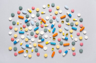 Gri arka planda farklı renkli haplar.