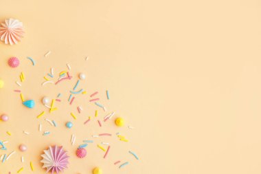 Bej arkaplana saçılmış kremalı tatlı renkli şekerler.