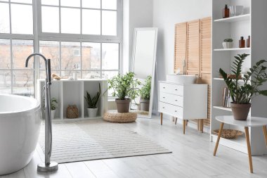 Açık banyonun içinde panoramik pencereli beyaz bir küvet.