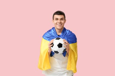 Pembe arka planda futbol topu ve Ukrayna bayrağı olan genç bir adam.