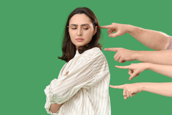 People pointing at young woman on green background. Accusation concept