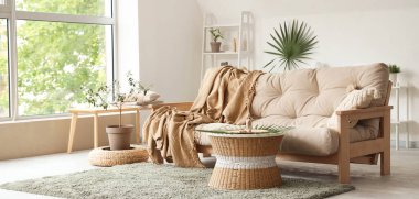 Aydınlık oturma odasının iç tarafında ekoseli bej bir kanepe.