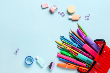 Renk arkaplan üzerinde alışveriş sepeti ve kırtasiye malzemesi olan kompozisyon