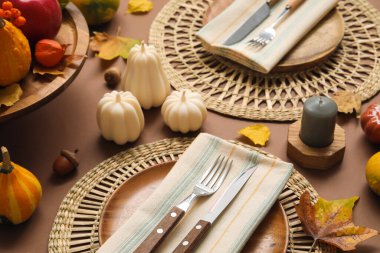 Kahverengi arkaplanda sonbahar dekoru ve mumlarla süslü masa ayarları