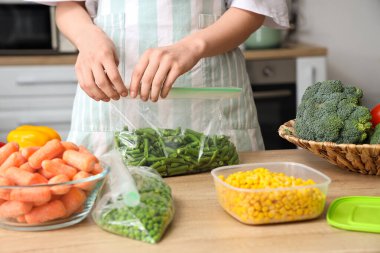 Mutfakta dondurmak için yeşil fasulyeli plastik poşet tutan kadın.