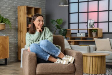 Mutlu genç kadın evde koltukta oturuyordu