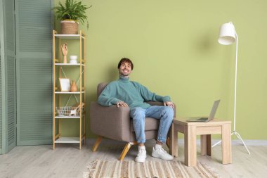 Evdeki yumuşak koltukta dinlenen yakışıklı adam.