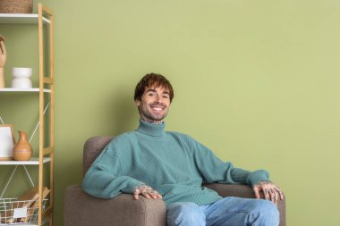 Evdeki yumuşak koltukta dinlenen yakışıklı adam.