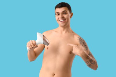 Mavi arka planda fotoepilatörü olan genç bir adam.