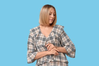 Mavi arka planda kısa saç stili olan güzel bir genç kadın.