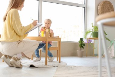 Oyuncaklı küçük kız psikoloğun ofisinde oturuyor.