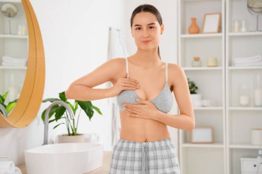 Banyoda göğüslerini kontrol eden genç bir kadın. Kanser farkındalığı kavramı