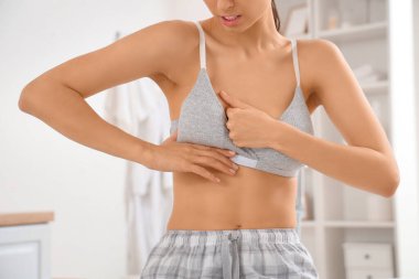 Banyoda göğüslerini kontrol eden genç bir kadın, yakın plan. Kanser farkındalığı kavramı