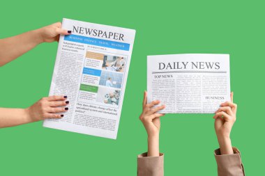 Female hands with newspapers on green background