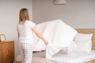 Yatak odasında yatak hazırlayan genç bir kadın.
