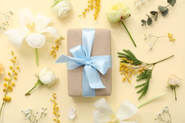 Kutlama hediye kutusu ve bej arka planda çiçekler.