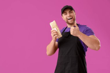 Lezzetli donör kebabı olan aşçı mor arka planda baş parmak hareketi gösteriyor.