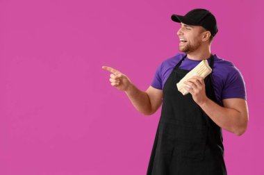 Lezzetli donör kebabı olan aşçı mor arka plandaki bir şeyi işaret ediyor.