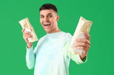 Yeşil arka planda lezzetli donör kebabı olan mutlu genç adam.