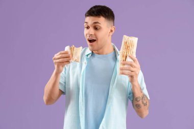 Lezzetli bir donör kebabı olan genç adam leylak arka planda.