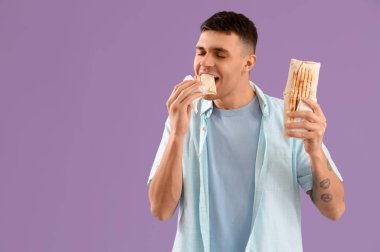 Leylak arka planında lezzetli donör kebabı yiyen yakışıklı genç adam.