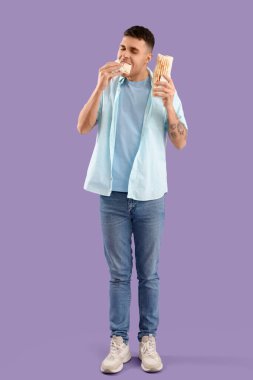 Leylak arka planında lezzetli donör kebabı yiyen yakışıklı genç adam.