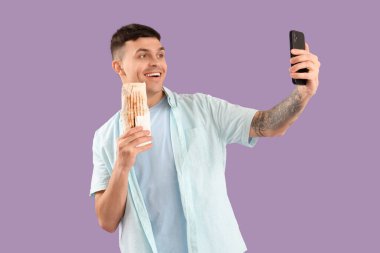 Lezzetli donör kebabı olan yakışıklı genç adam leylak arka planda selfie çekiyor.