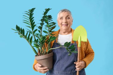Mavi arka planda bitki ve kürek taşıyan bahçıvan.
