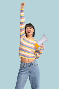 Mavi arka planda megafonu olan mutlu genç bir kadın.