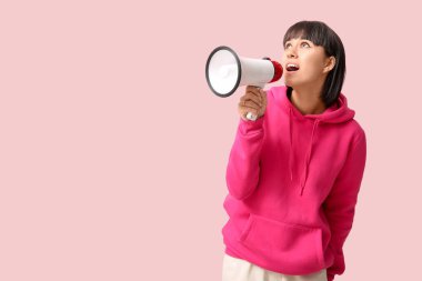 Pembe arka planda megafonu olan şaşırmış genç bir kadın.