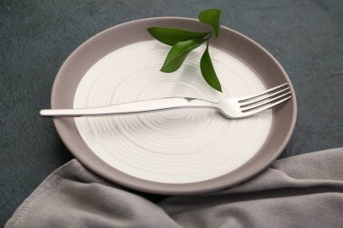 Çatallı temiz tabak ve siyah arka planda yapraklar.