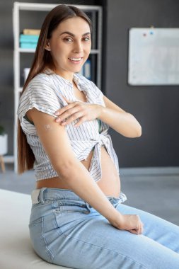 Klinikte aşıdan sonra yamayla gezen hamile genç bir kadın.