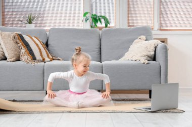 Cute little ballerina training with laptop at home