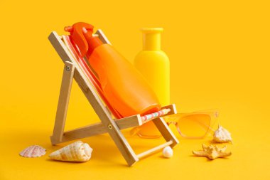 Güverte sandalyesi, güneş kremi şişeleri, deniz kabukları ve renkli arka plan gözlüğü.