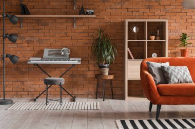 Turuncu kanepesi, halısı ve raf ünitesi olan bir çatı katı tarzı oturma odası.