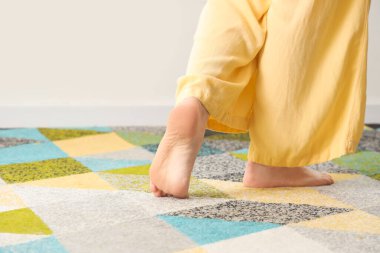 Çıplak ayaklı kadın renkli halıda yürüyor.