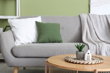 Rahat kanepesi, ekoseli, yastığı ve kahve masası olan yeşil oturma odası.