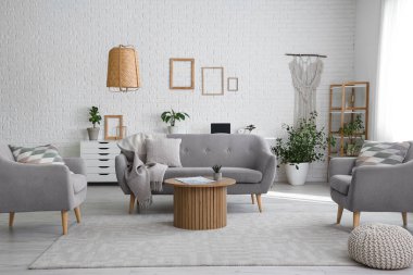 Beyaz oturma odasının içinde rahat bir kanepe, koltuklar ve kahve masası var.