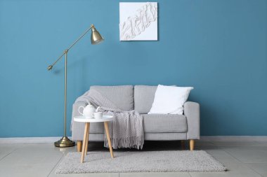 Gri kanepe, lamba ve resimli mavi oturma odasının şık bir iç mekanı.