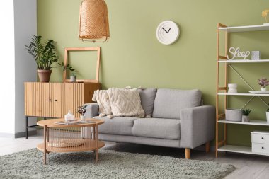 Gri kanepeli, çekmeceli, raf üniteli ve kahve masalı şık bir oturma odası.