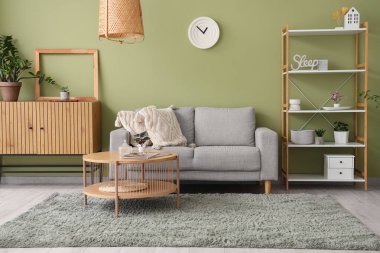 Gri kanepeli, çekmeceli, raf üniteli ve kahve masalı şık bir oturma odası.