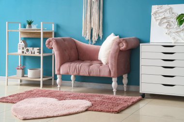 Yumuşak koltuğu, halısı, yastığı ve çekmeceleri olan mavi oturma odasının şık bir iç mekanı.