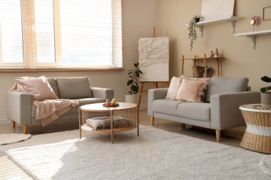 Gri kanepeleri, halısı, resimleri ve sehpası olan aydınlık oturma odası.