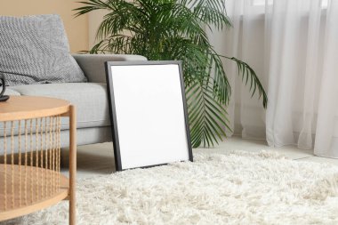 Rahat kanepeli, çiçekli ve boş çerçeveli şık bir oturma odası.