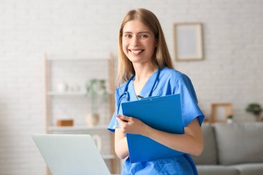 Evde dizüstü bilgisayarı ve panosu olan bir kadın stajyer.