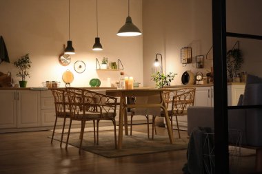 Parlayan lambaları, beyaz tezgahları, sandalyeleri ve akşam yemeği masası olan modern mutfağın içi.