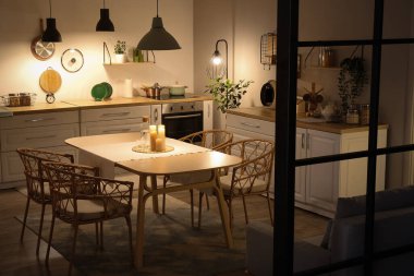 Parlayan lambaları, beyaz tezgahları, kanepesi ve akşam yemeği masası olan modern mutfağın içi.