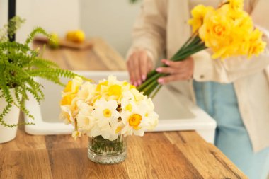 Genç kadın ve güzel narsisli buketler evde, yakın çekim.