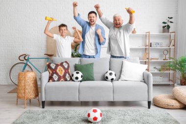 Babası ve oğlu evde futbol takımı için tezahürat yapan bir adam.